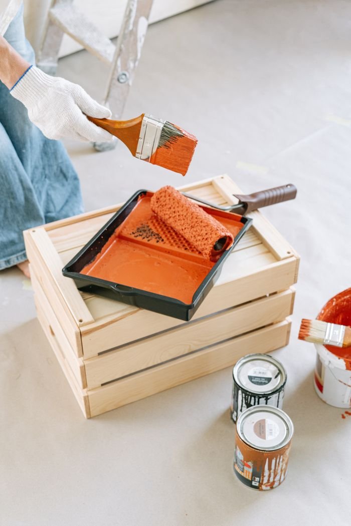 A collection of painting tools including brushes and rollers on a wooden crate, ideal for DIY home improvement.