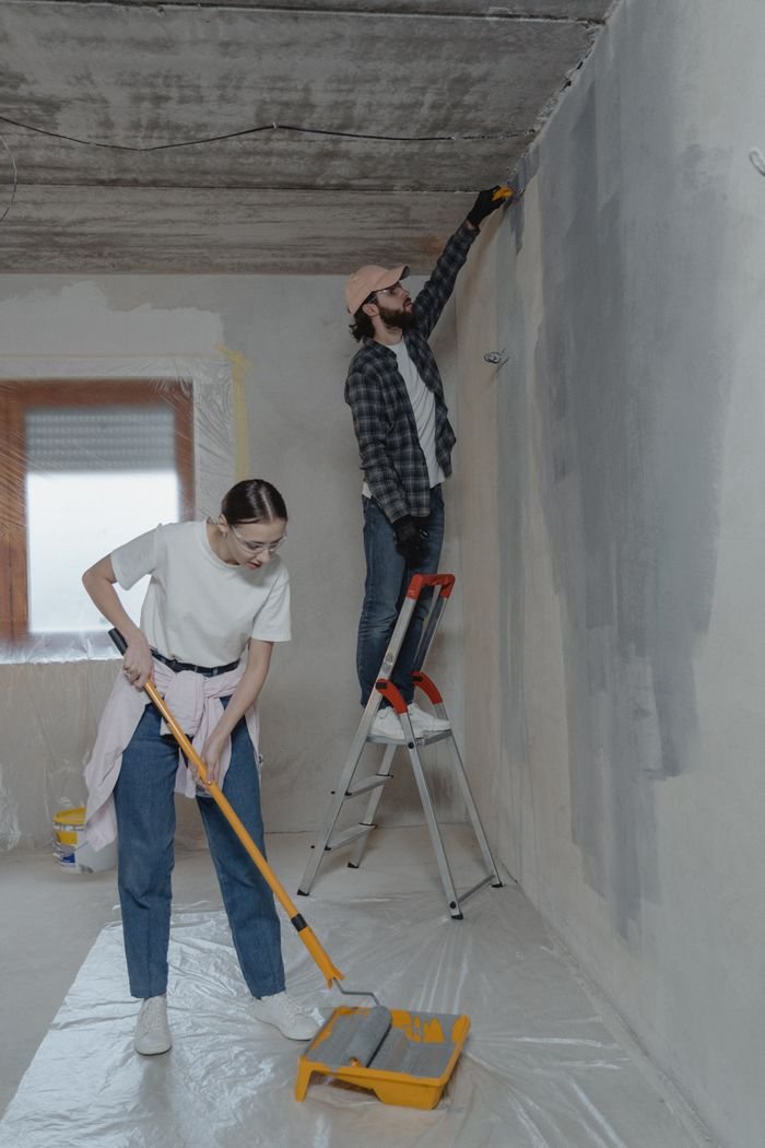 Young couple painting walls and doing home renovation together.